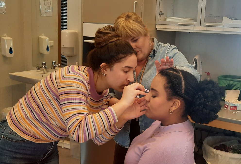 Förðun krefst mikillar einbeitingar. Margrét Bergmann Tómasdóttir kennari fylgist með.