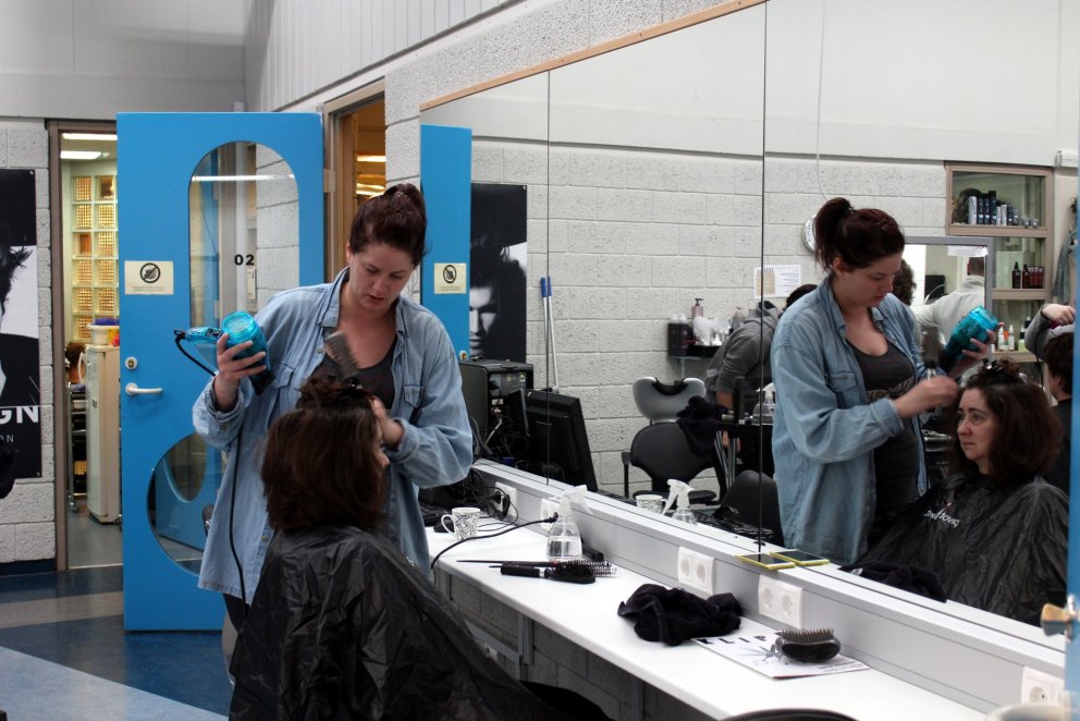 Með blásarann á lofti í rými hársnyrtibrautar.