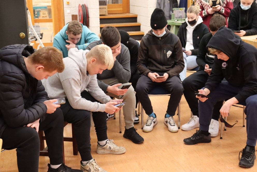 Bingóspenntir nemendur rýna í símana.