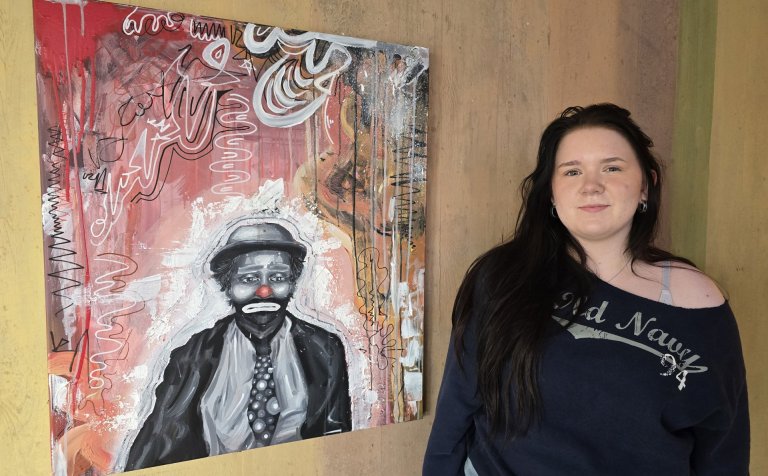 Liv Sólrún Bastiansdóttir Stange við akrílmyndina sína, sem nú er til sýnis á vegg við austurinngang…