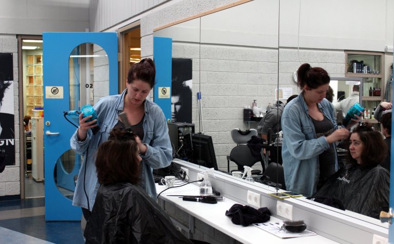 Með blásarann á lofti í rými hársnyrtibrautar.