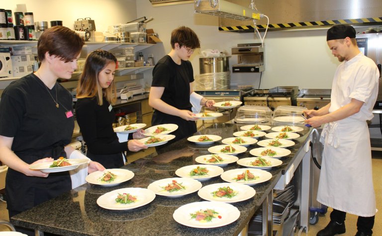 Nemendur leggja lokahönd á framreiðslu matarins.