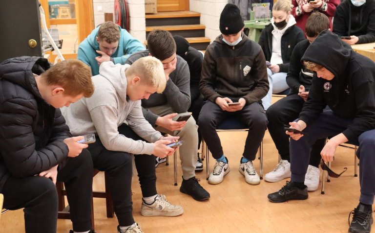 Bingóspenntir nemendur rýna í símana.